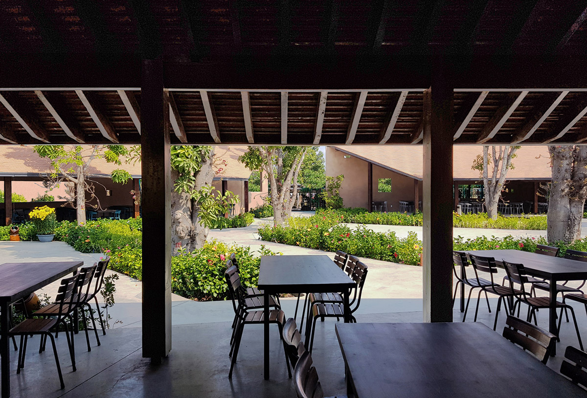 TAA DESIGN built public space with pitched roofs and rough concrete walls painted with pink tones