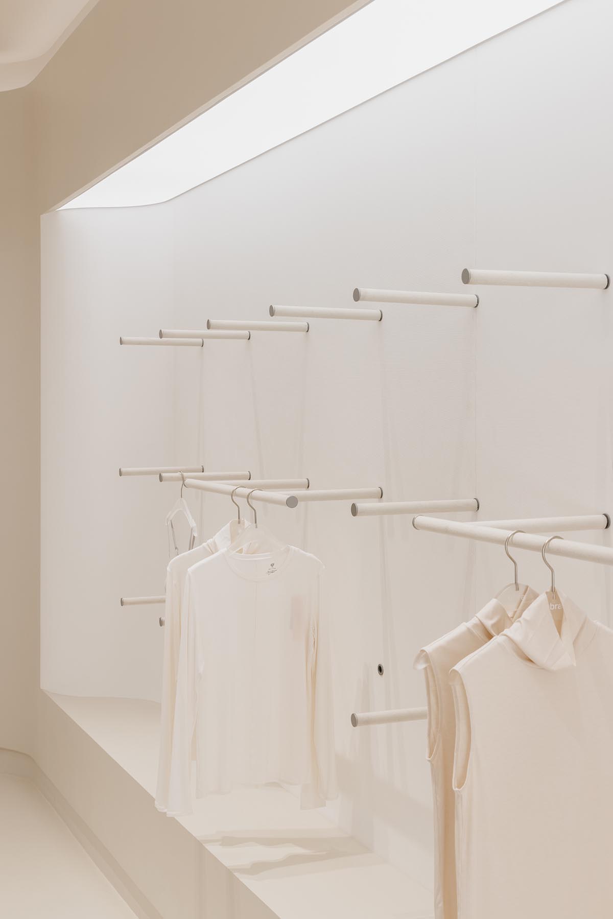 Store interiors by Sò Studio feature soft beige tones to give the feeling of