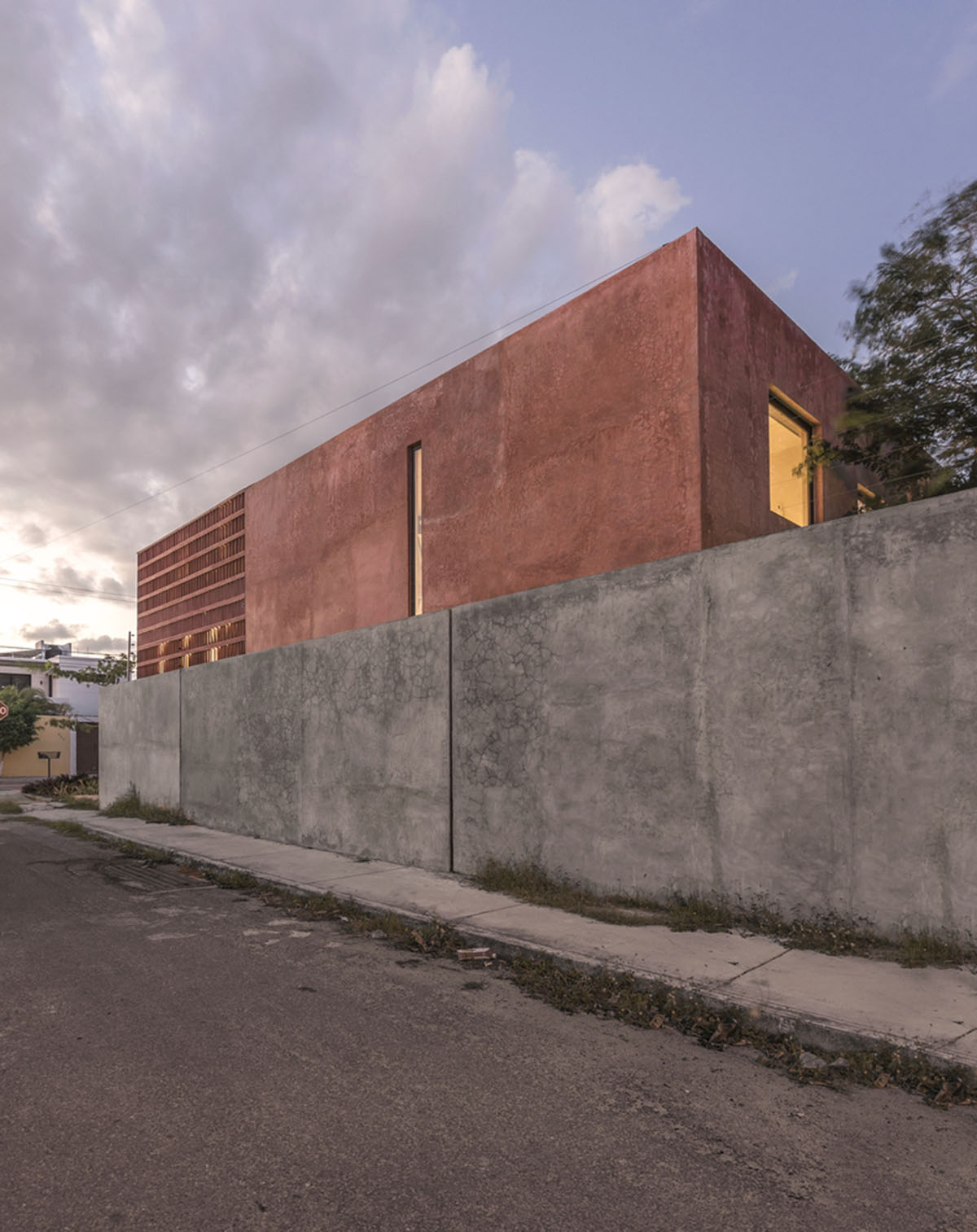 Red pigmented lattice wall creates contrast with gray concrete base in  Bugambilias House in Mexico