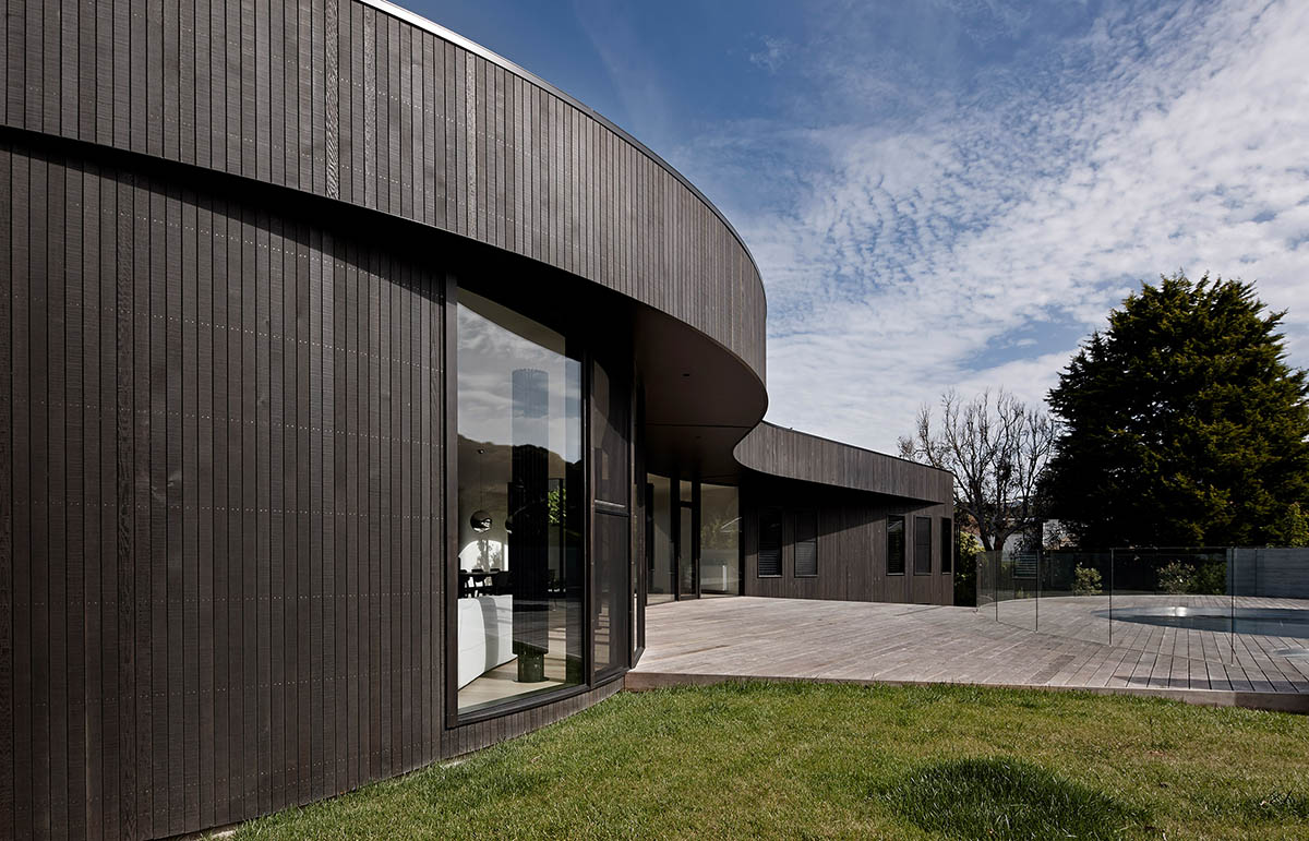 Wood Marsh built curvaceous home clad in dark timber contrasting its natural landscape in Portsea