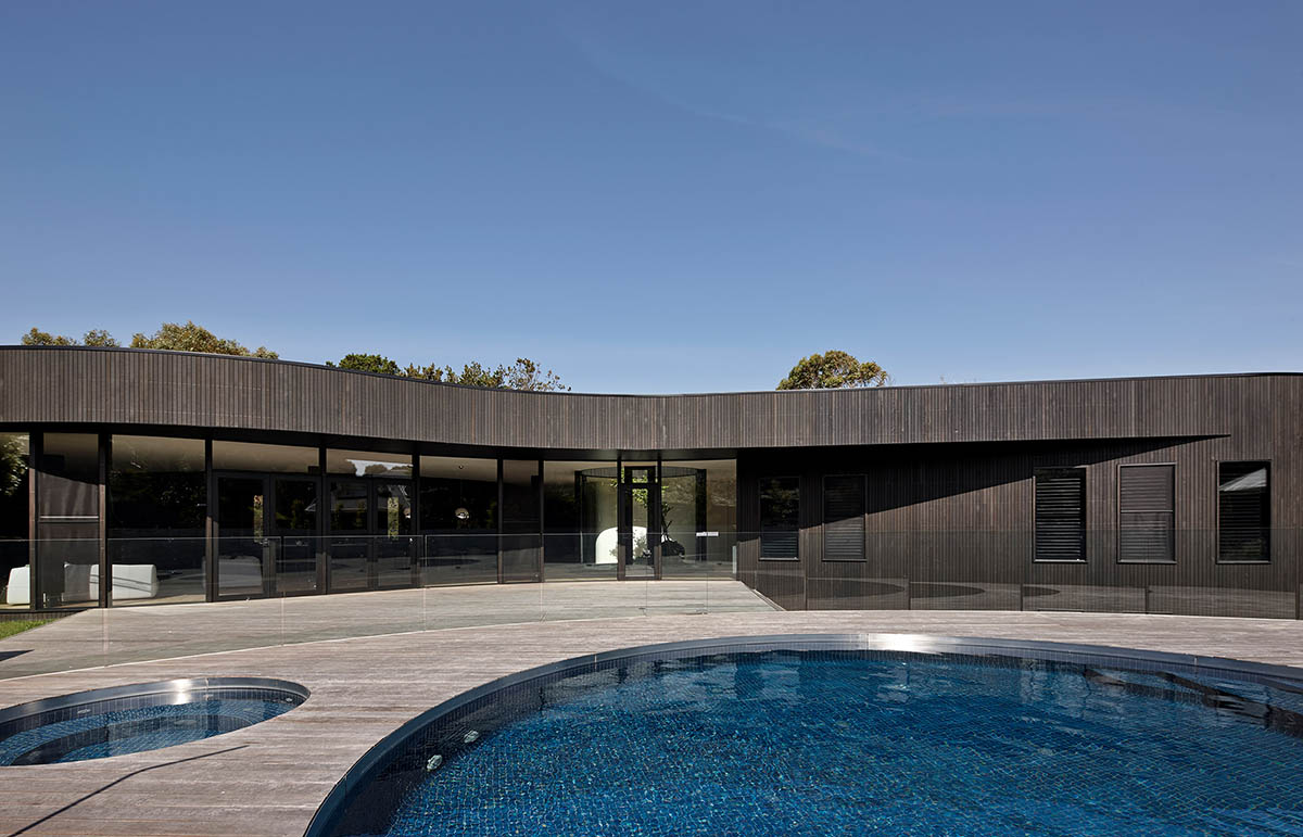 Wood Marsh built curvaceous home clad in dark timber contrasting its natural landscape in Portsea