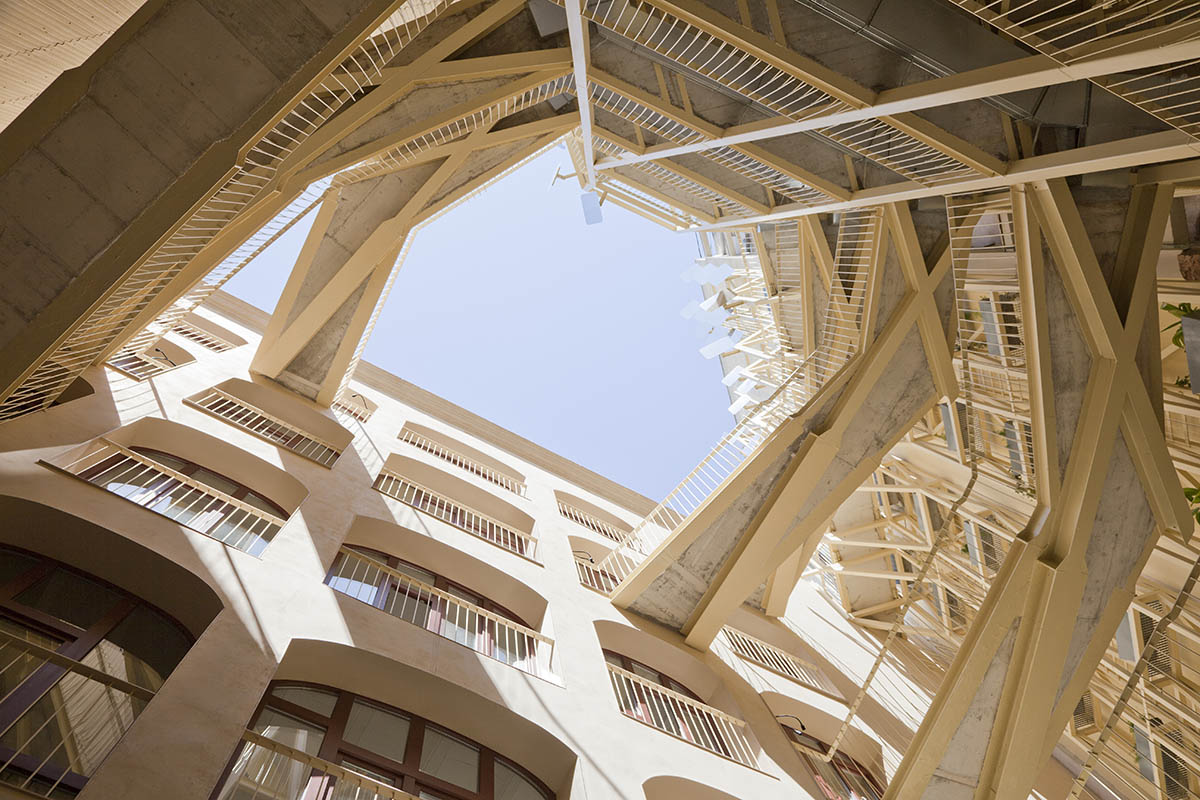 La Carboneria housing block features a dramatic courtyard with crossing beams in Barcelona