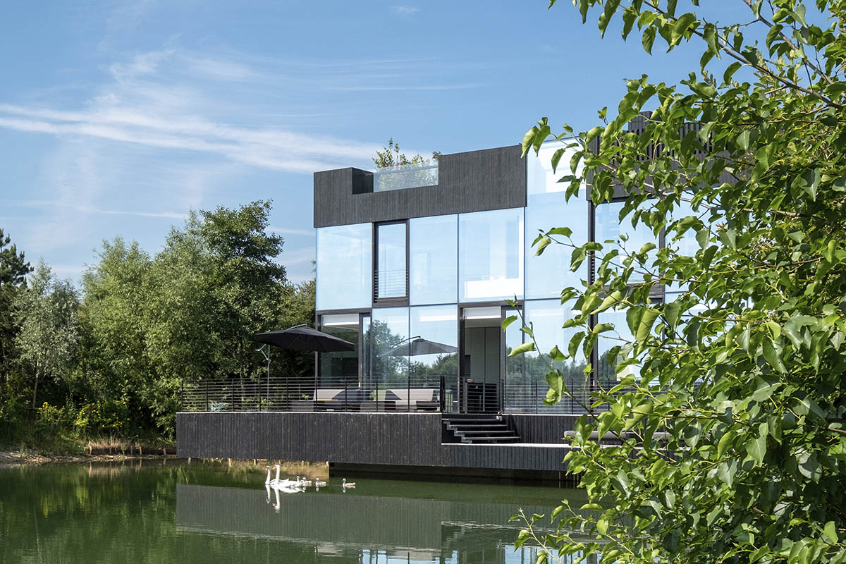 Mecanoo completes glass villa with dark stripes on a lake in Lechlade