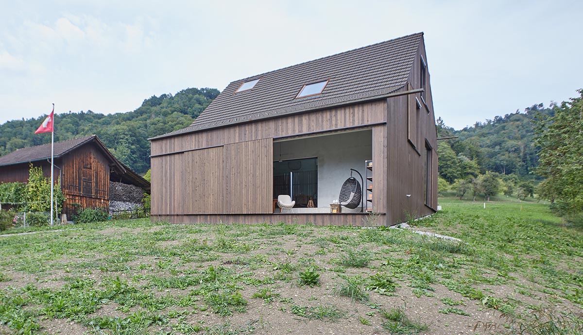 Residential barn features an unfinished, raw interior in Swiss rural landscape