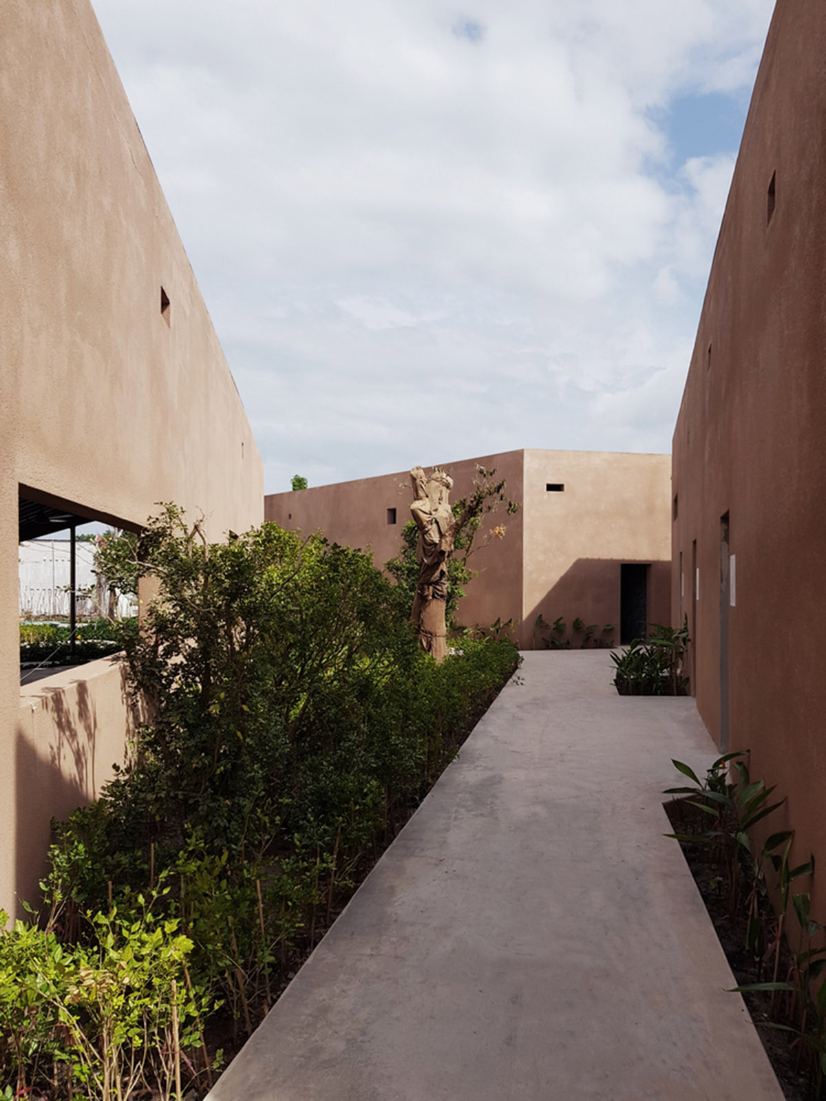 TAA DESIGN built public space with pitched roofs and rough concrete walls painted with pink tones