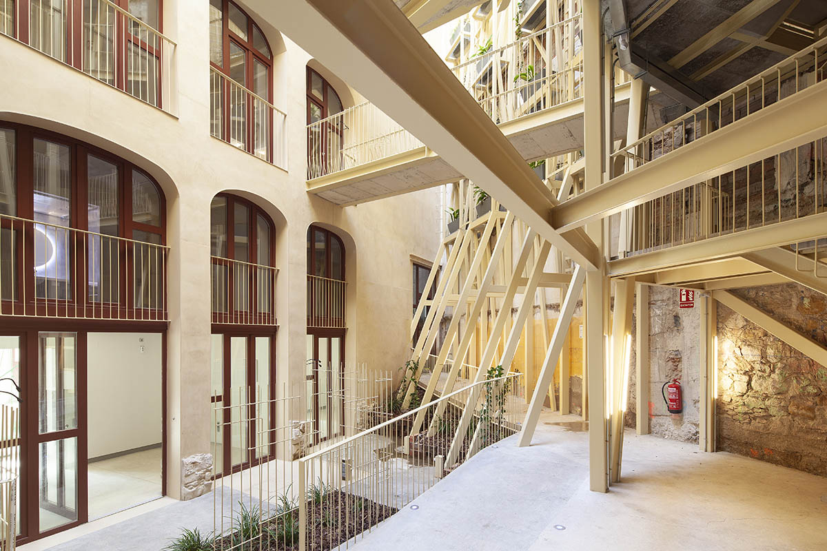 La Carboneria housing block features a dramatic courtyard with crossing beams in Barcelona 