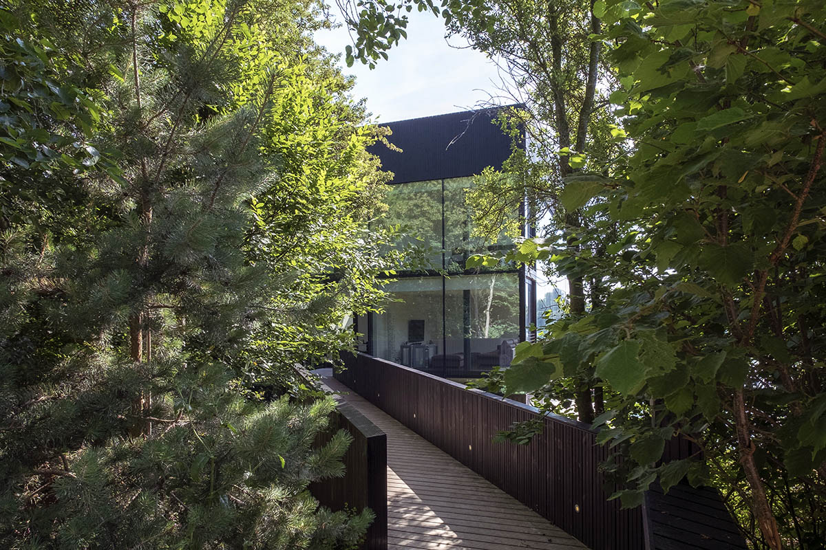 Mecanoo completes glass villa with dark stripes on a lake in Lechlade