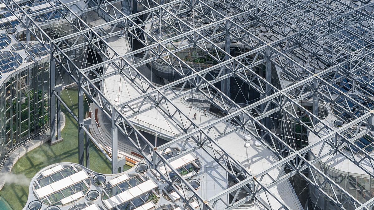 The former steelworks of a power plant are integrated with organically-shaped greenhouse pavilions