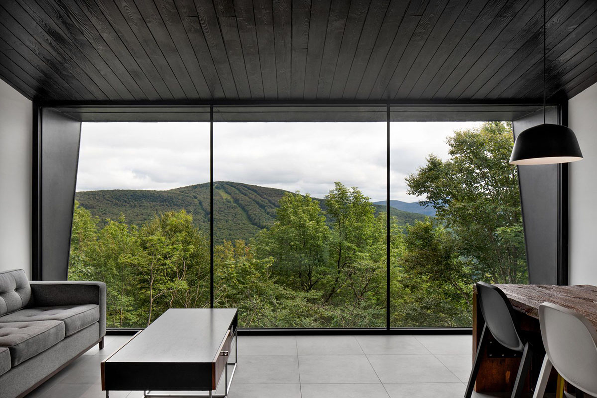 Two black wooden holiday cabins by Naturehumaine perched on a mountain of Quebec
