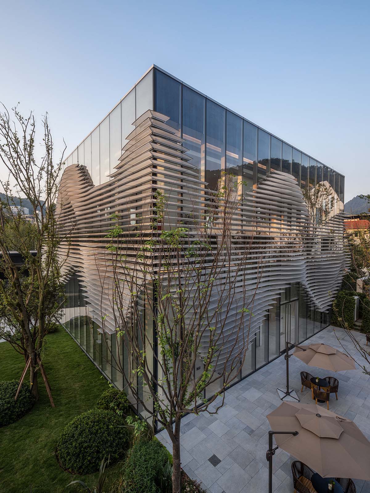 aoe wraps this sales pavilion with perforated plates that create a long scroll landscape painting