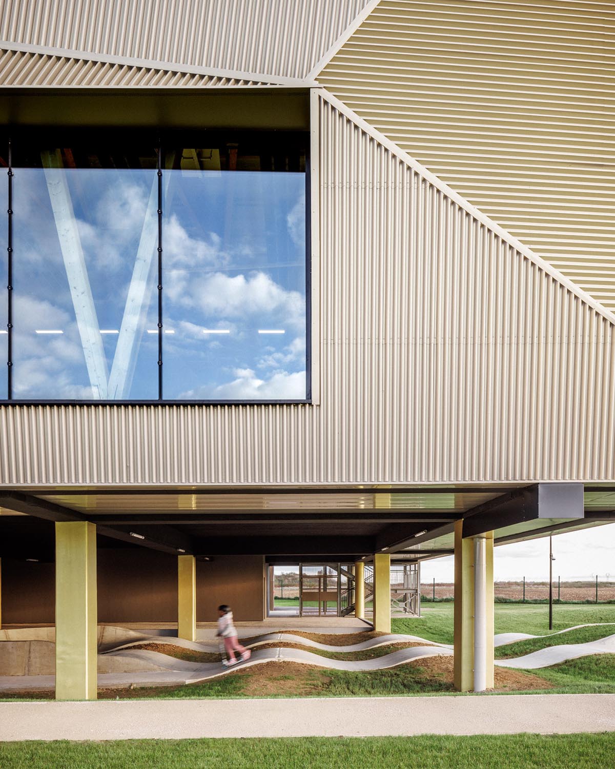 The gold-colored, folded facade gives a striking and symbolic presence to a new sports complex 