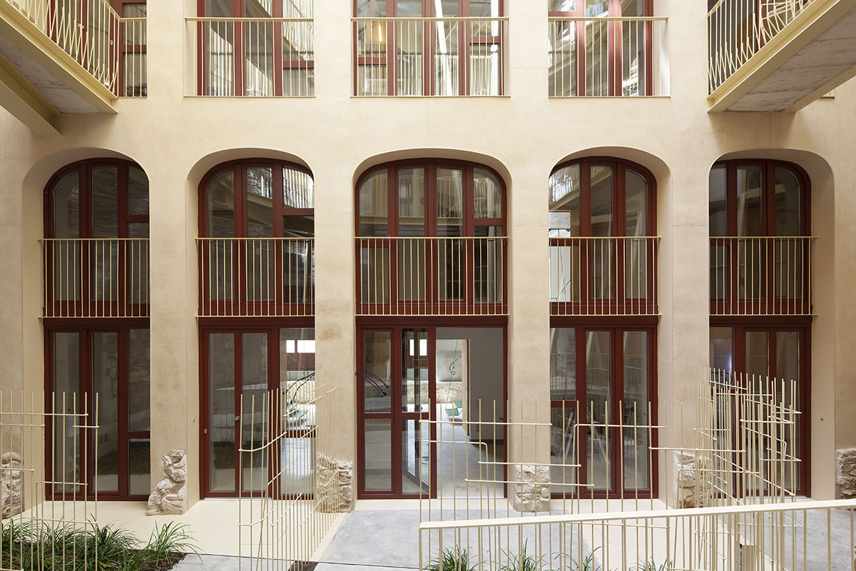 La Carboneria housing block features a dramatic courtyard with crossing beams in Barcelona