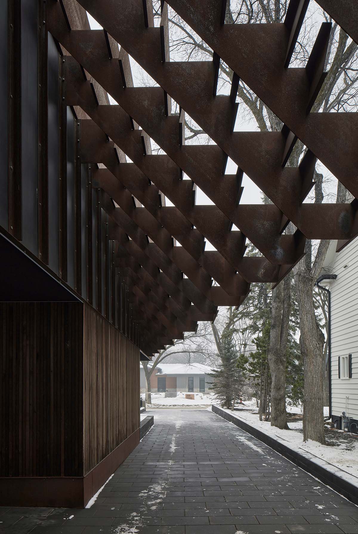 Weathered steel weil wraps the façade of Veil House in to resist snowfalls in Winnipeg