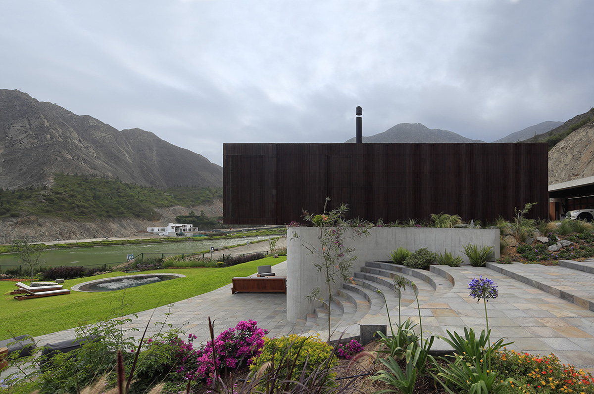 Large semi-buried social space creates a rustic and organic feeling under wooden volume built in Peru