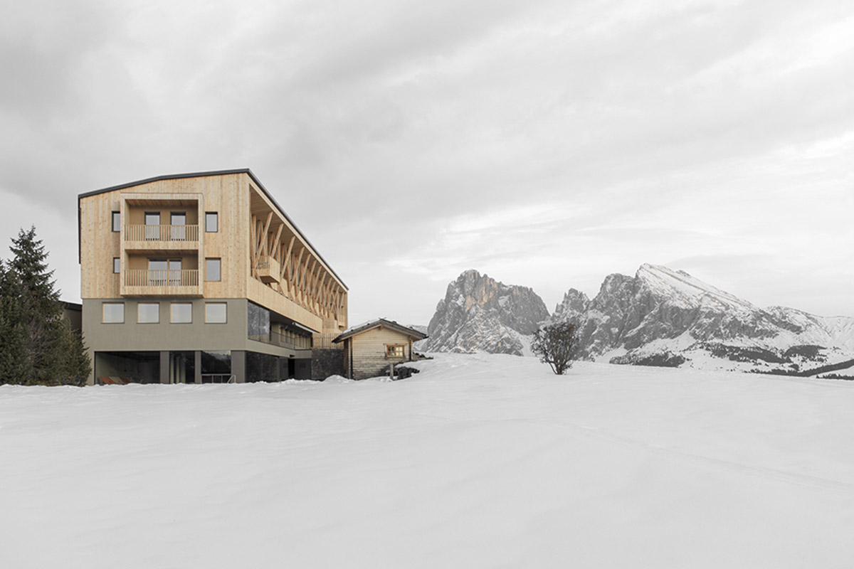 Icaro Hotel featuring wooden colonnade frames embraces alpine heritage landscape in Italy 