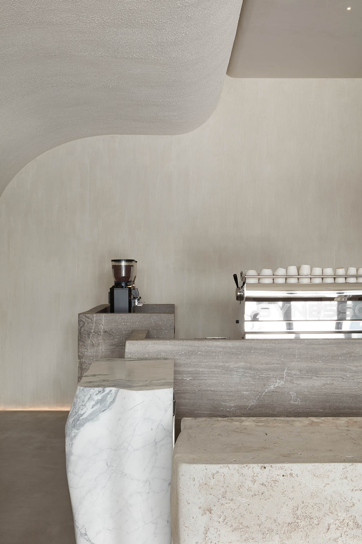 Интерьер кофейни от VSHD с большими каменными блоками неправильной формы и изогнутым потолком в Дубае.
