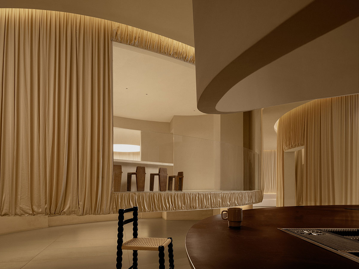 Tea house interiors wrapped by earth-toned fabric curtains act like 