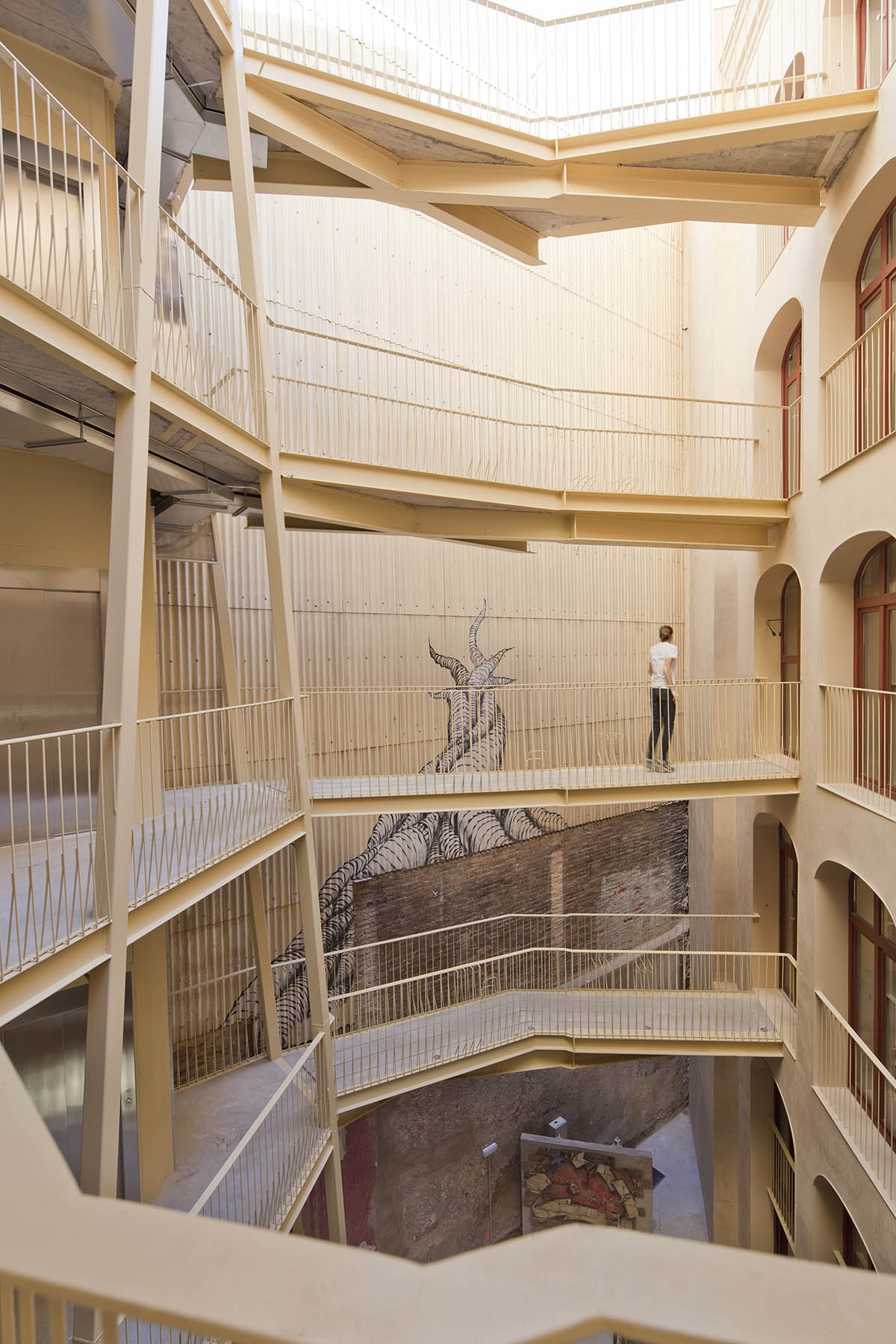 La Carboneria housing block features a dramatic courtyard with crossing beams in Barcelona 