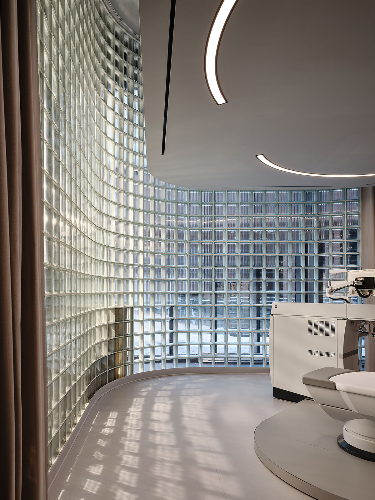 Eye care clinic features a sweeping glass block wall to disperse light in the interior