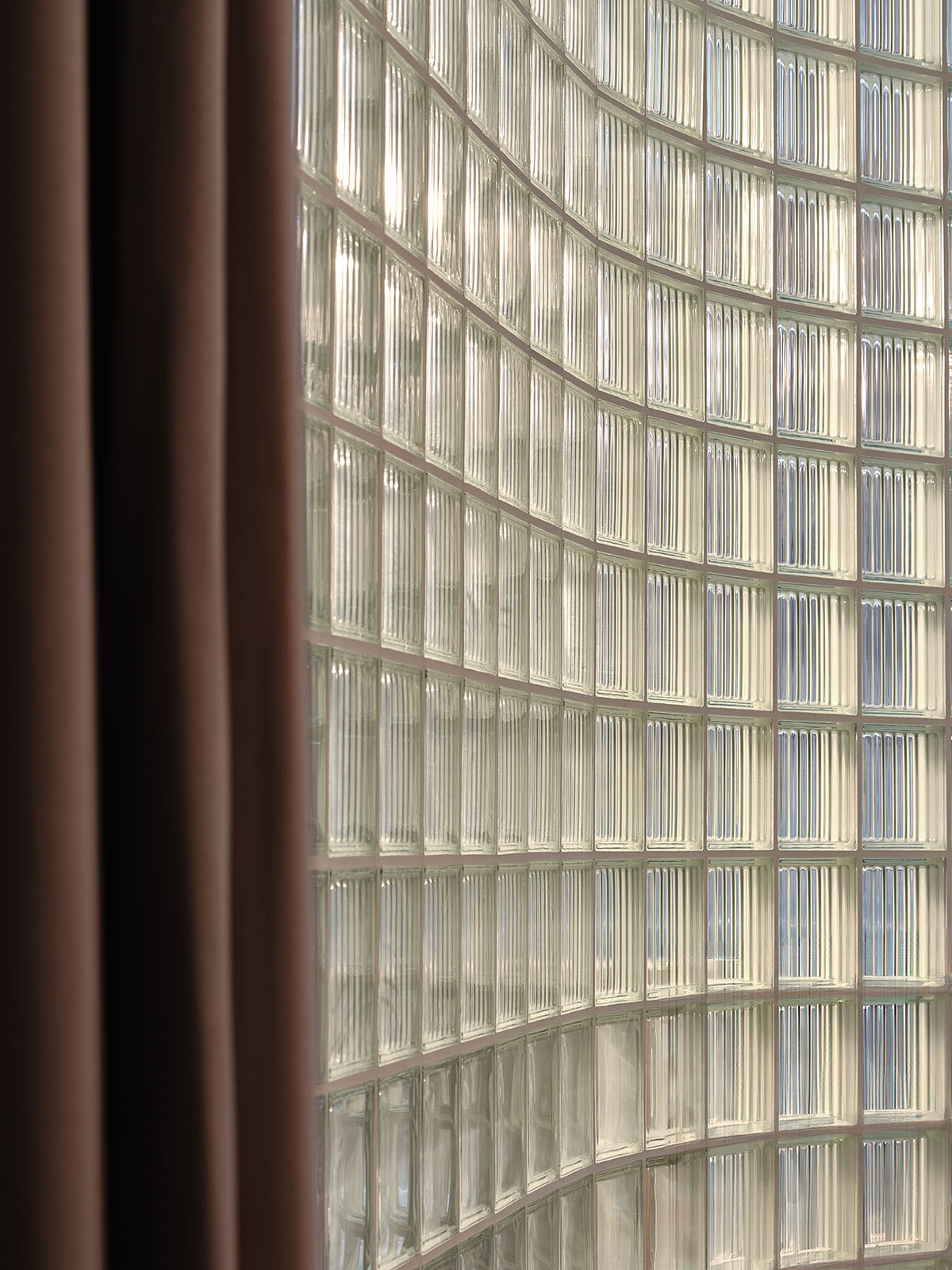 Eye care clinic features a sweeping glass block wall to disperse light in the interior