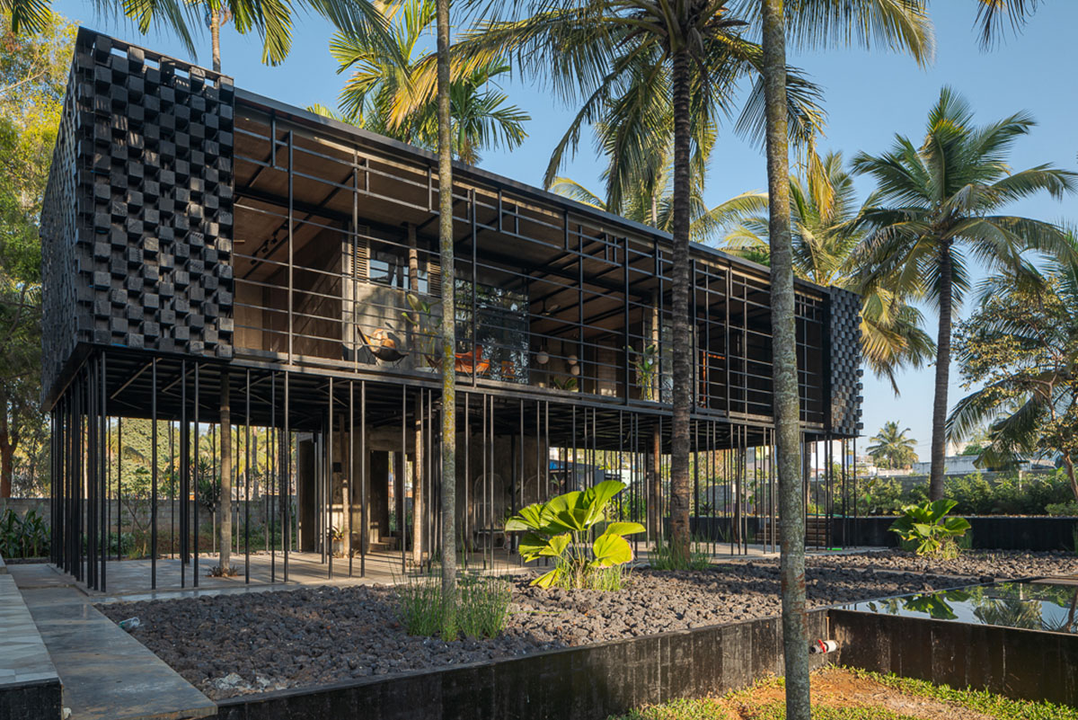 Parallax designs black weekend house raised on slender stilts within coconut trees in Bangalore