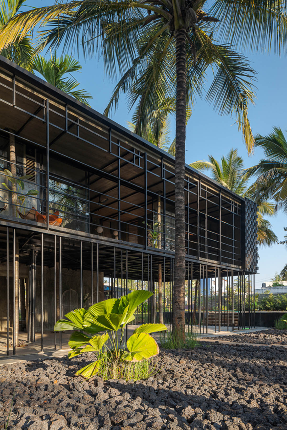 Parallax designs black weekend house raised on slender stilts within coconut trees in Bangalore