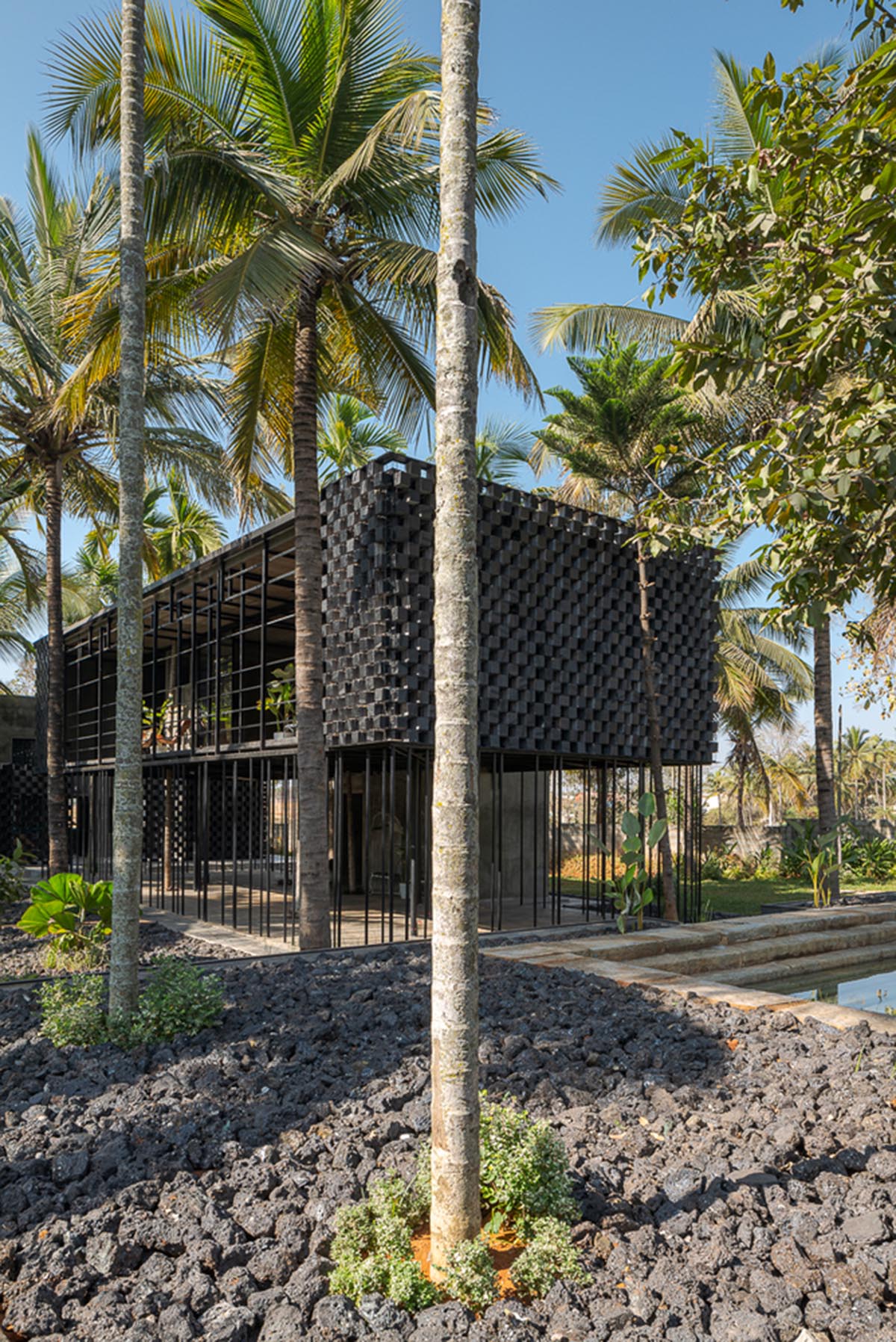 Parallax designs black weekend house raised on slender stilts within coconut trees in Bangalore
