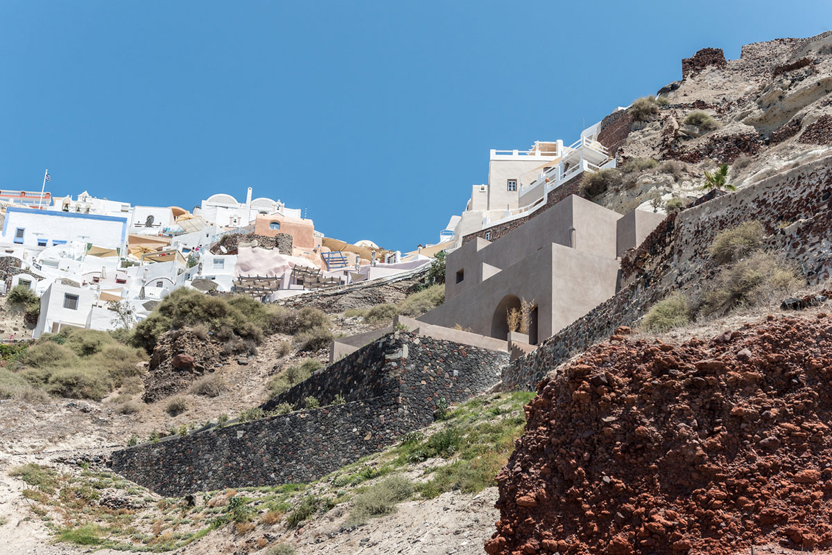 Kapsimalis Architects built castle-like hotel almost disappearing it on a steep hillside of Oia