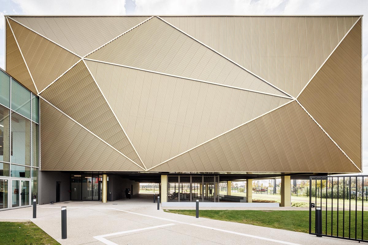 The gold-colored, folded facade gives a striking and symbolic presence to a new sports complex 