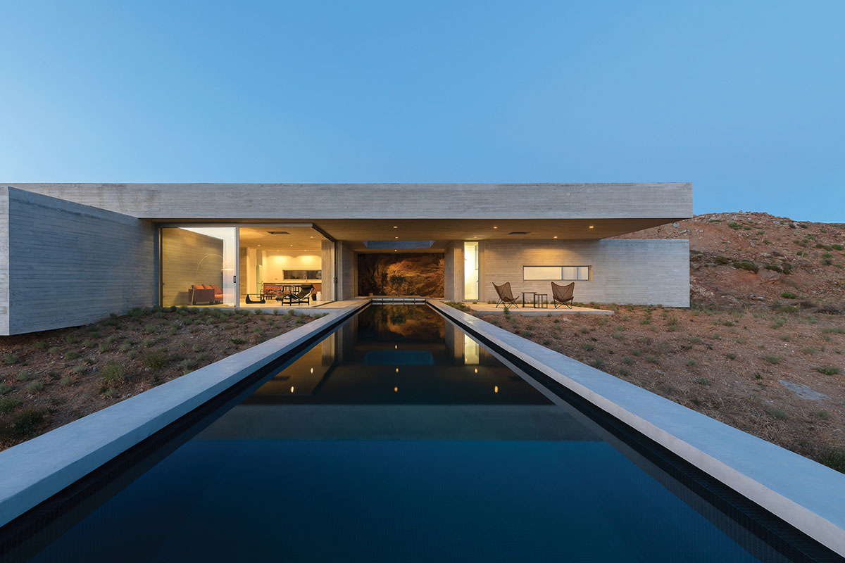 Swimming pool is bravely extended from inside of this concrete house towards endless view in Tinos