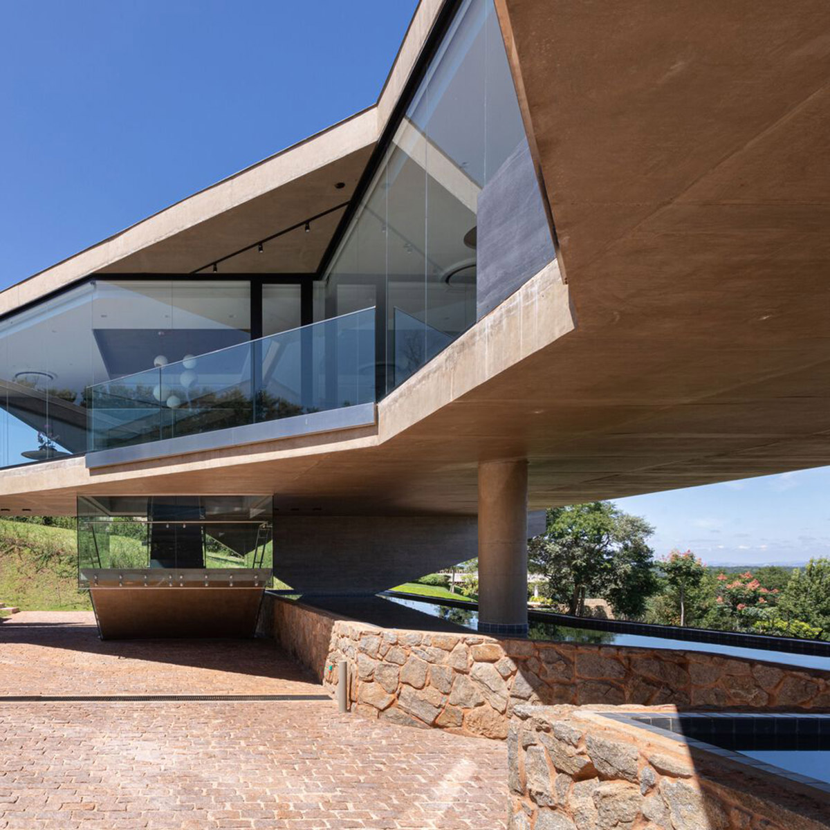 Bridge-like Brazilian house by Yuri Vital is supported by angular structural walls on sloped terrain