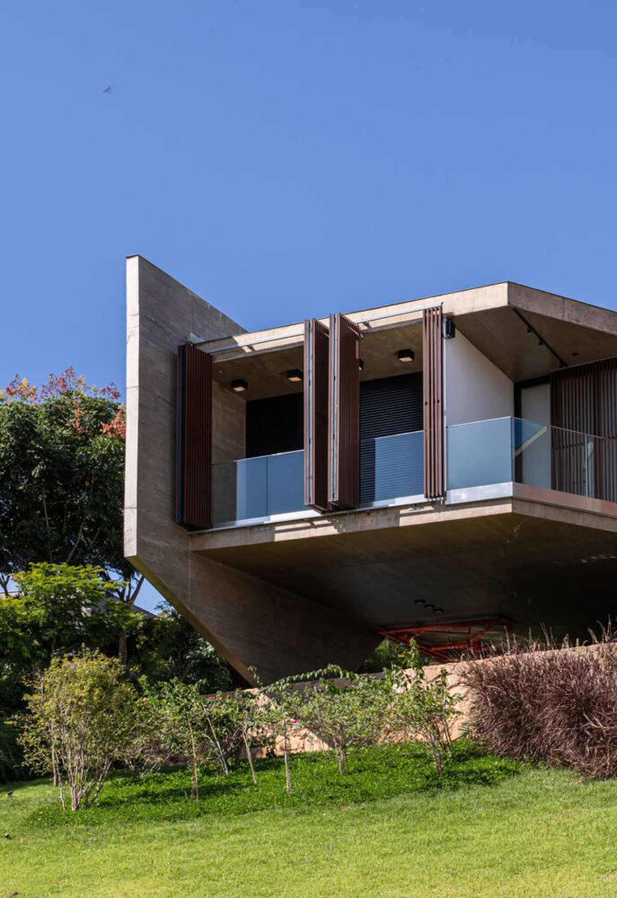 Bridge-like Brazilian house by Yuri Vital is supported by angular structural walls on sloped terrain