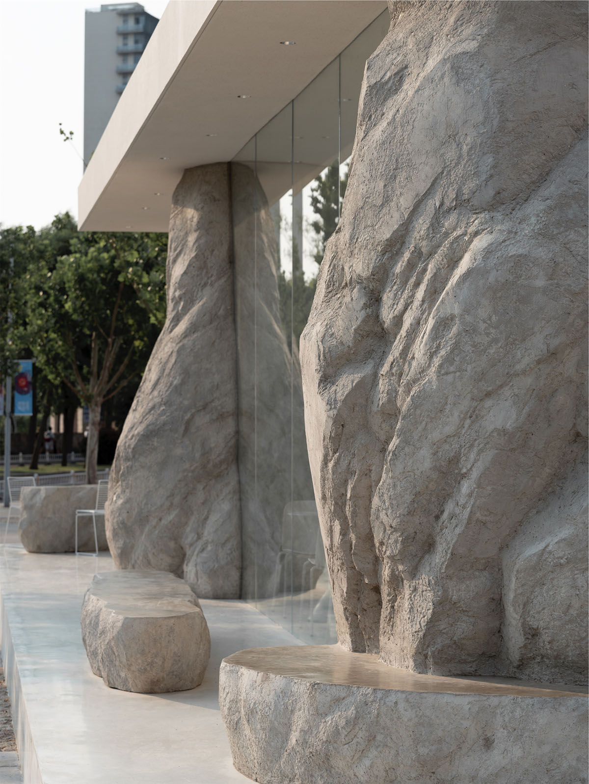 B.L.U.E. Architecture Studio adds a glazed cafe by using organic forms of stones to an open plaza