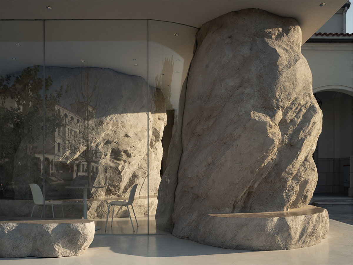 B.L.U.E. Architecture Studio adds a glazed cafe by using organic forms of stones to an open plaza