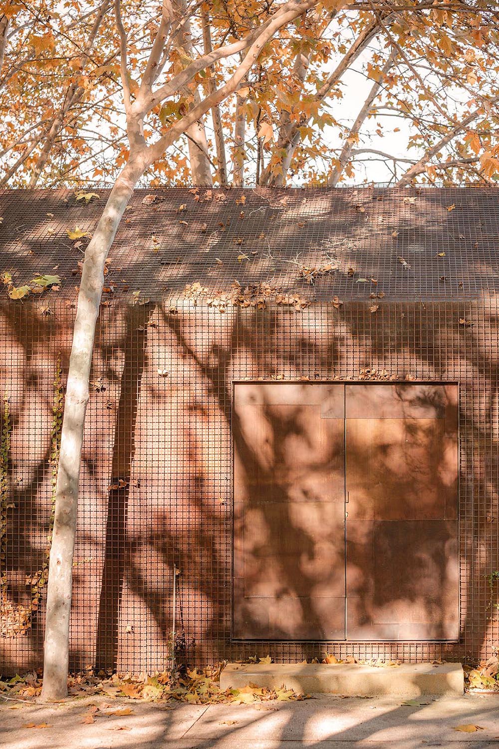 Beta.&Oslash; covers tennis and school buildings with varnished steel sheets and mesh to mimic the landscape