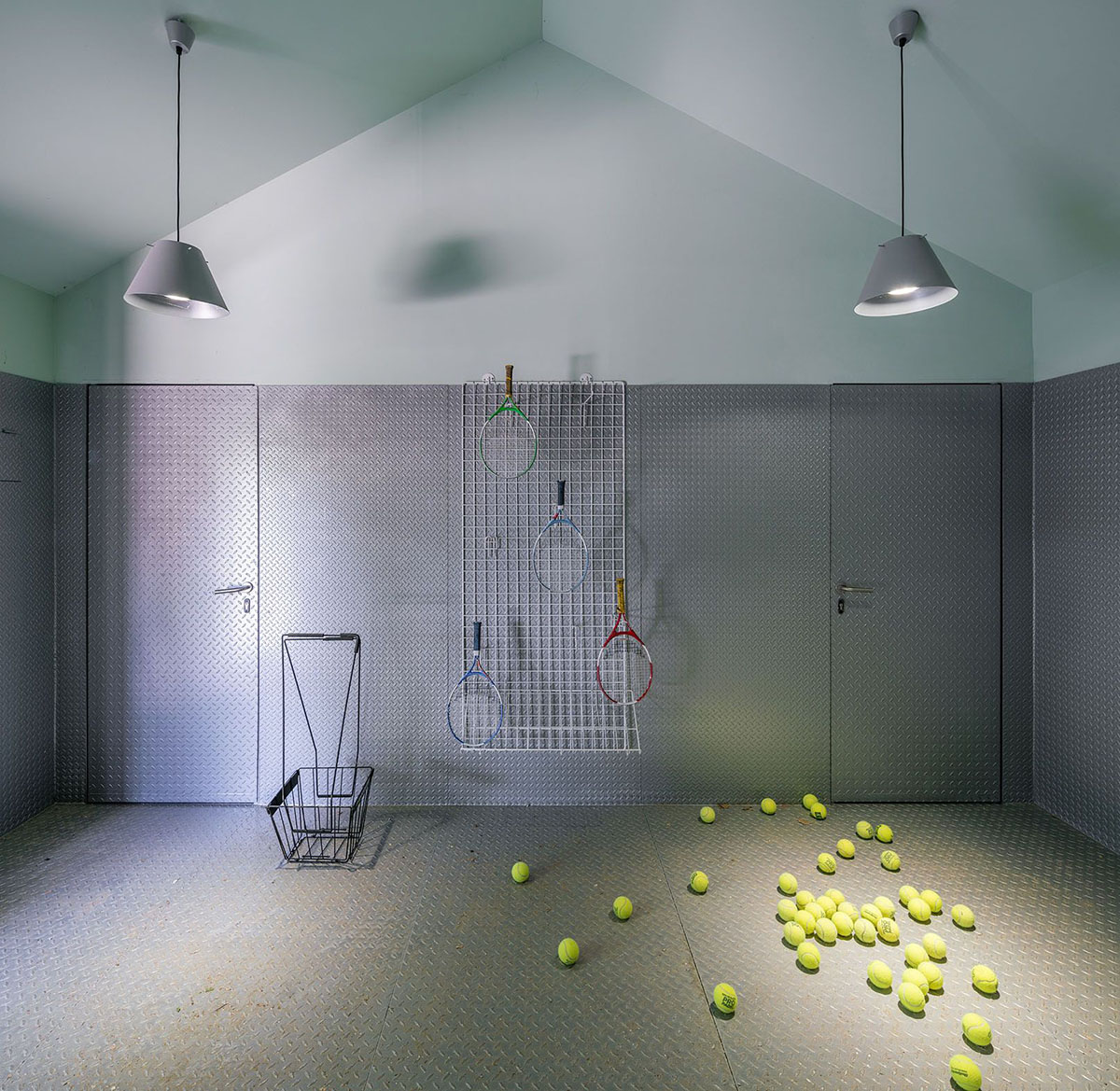 Beta.&Oslash; covers tennis and school buildings with varnished steel sheets and mesh to mimic the landscape