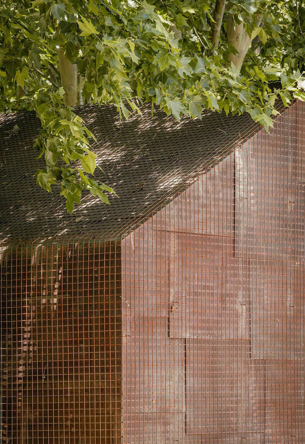 Beta.&Oslash; covers tennis and school buildings with varnished steel sheets and mesh to mimic the landscape