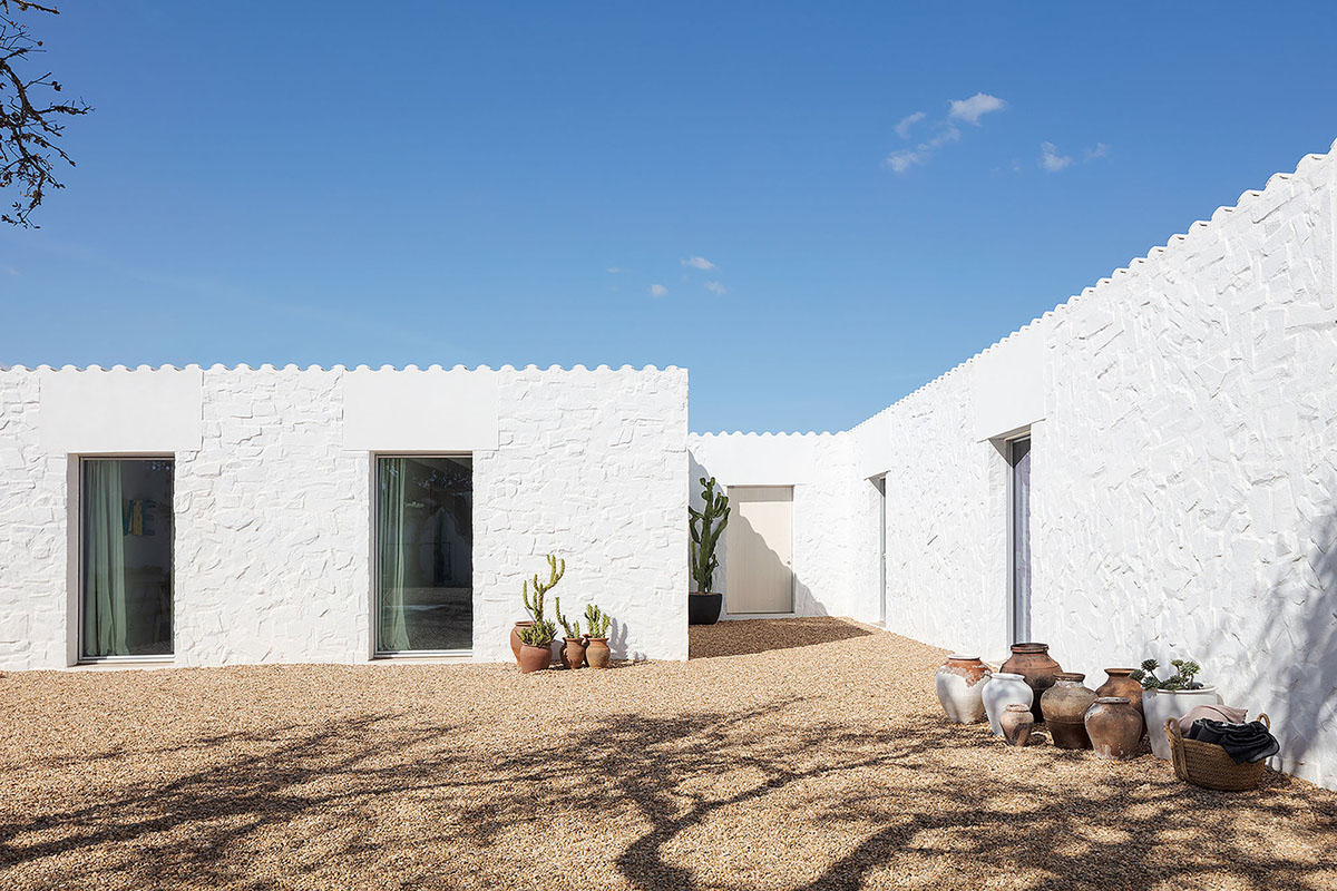 Low-profiled whitewashed stone walls wrap living units of Casa da Volta by PROMONTORIO and João Cravo