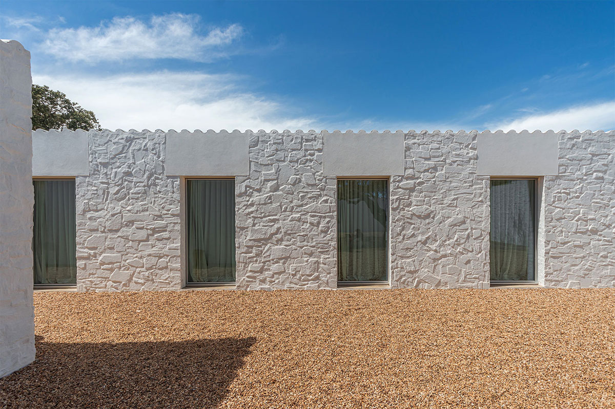 Low-profiled whitewashed stone walls wrap living units of Casa da Volta by PROMONTORIO and João Cravo