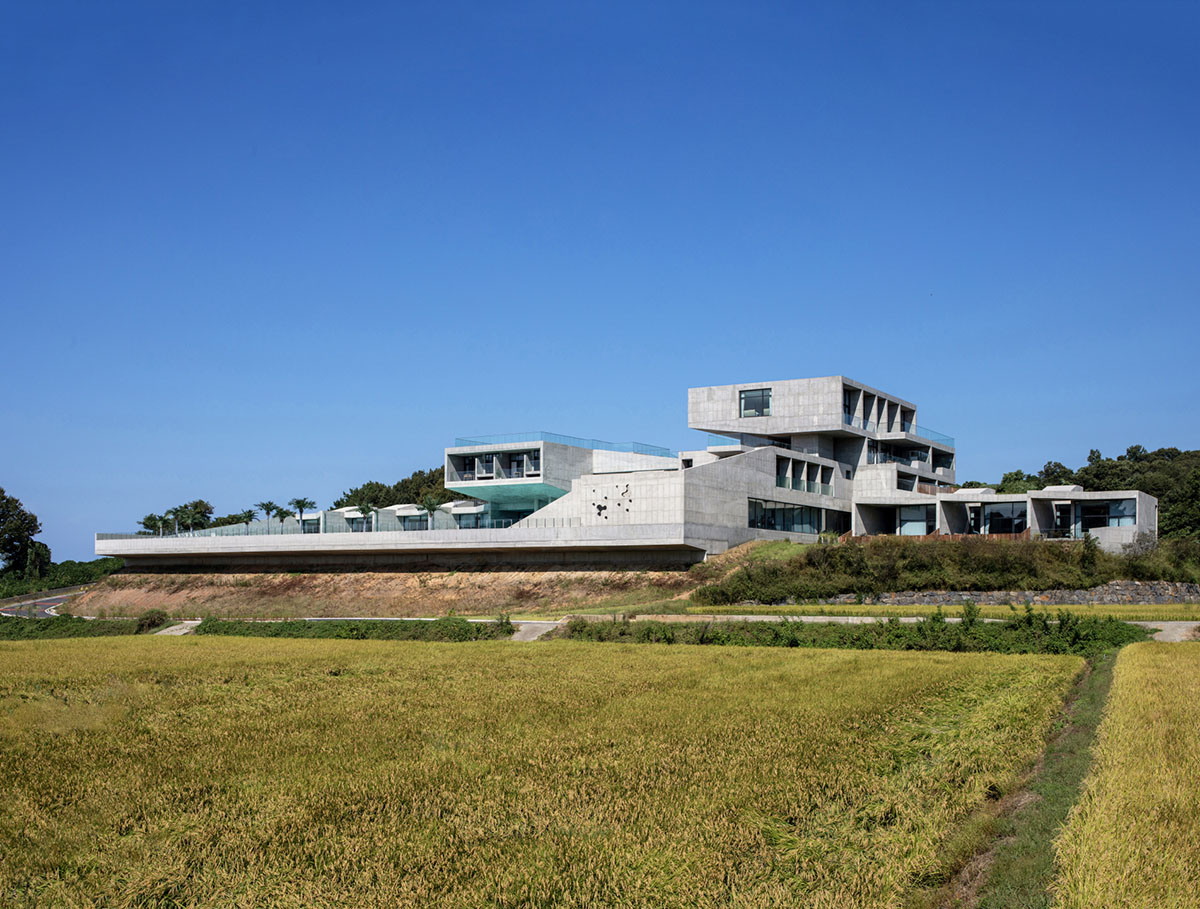 Elystay Resort is a striking horizontal concrete volume amidst scenic rural farmland in South Korea