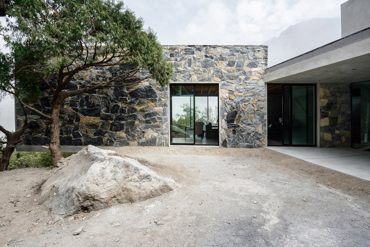 P+0 Arquitectura designs residence mixed with concrete and stone volumes on a complex terrain