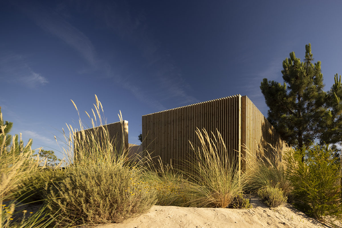 Palisade House is wrapped by a long palisade in fir wood to protect dunes in Troia, Portugal 