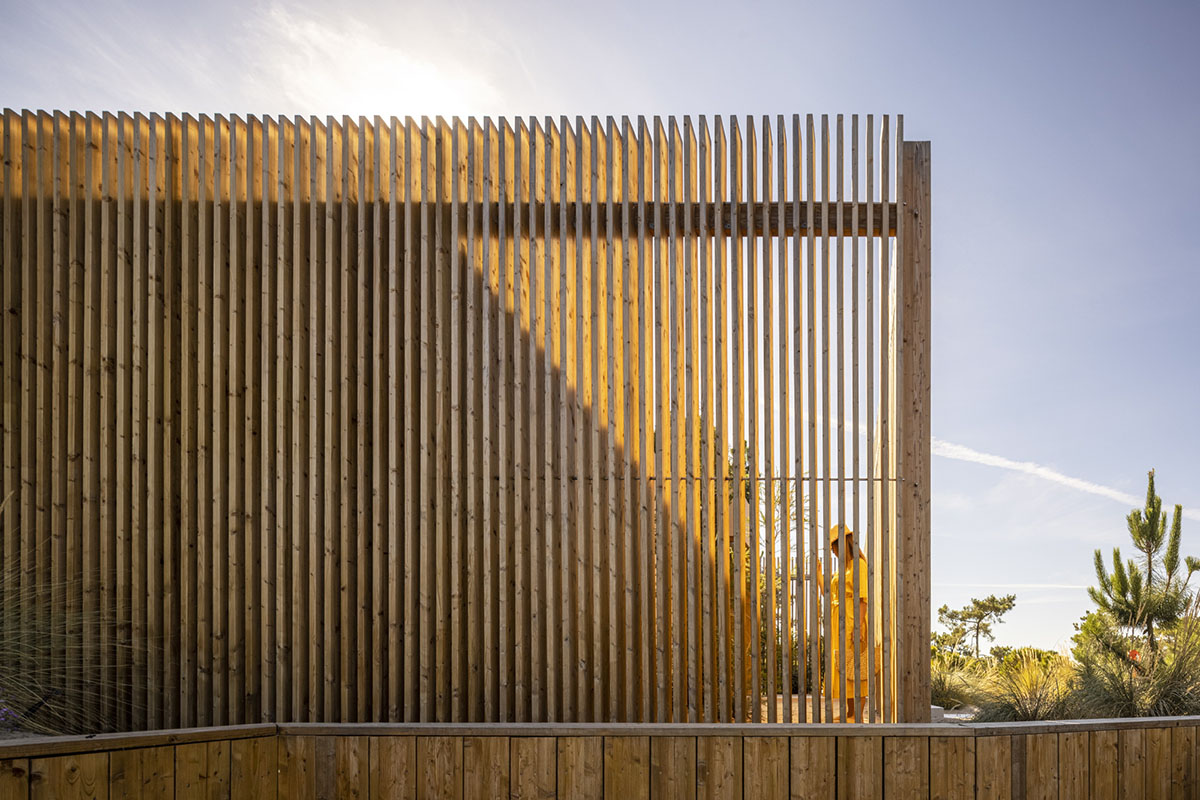 Palisade House is wrapped by a long palisade in fir wood to protect dunes  in Troia