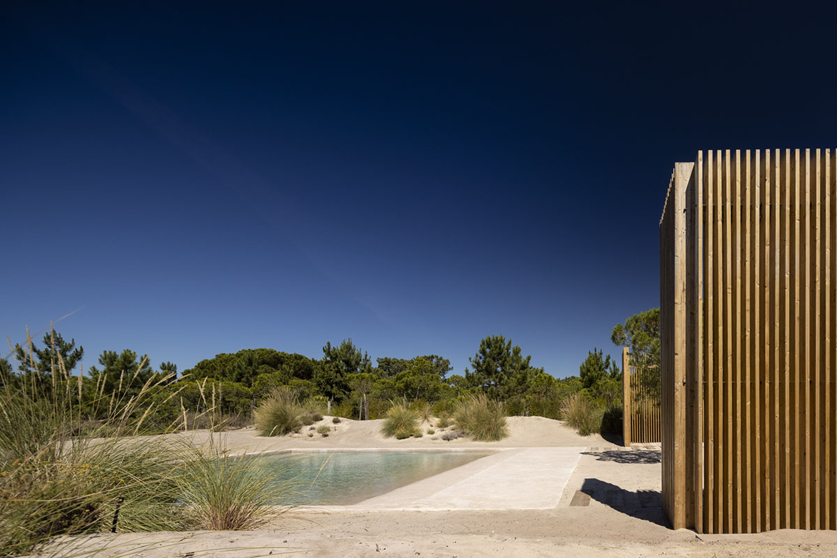 Palisade House is wrapped by a long palisade in fir wood to protect dunes in Troia, Portugal 