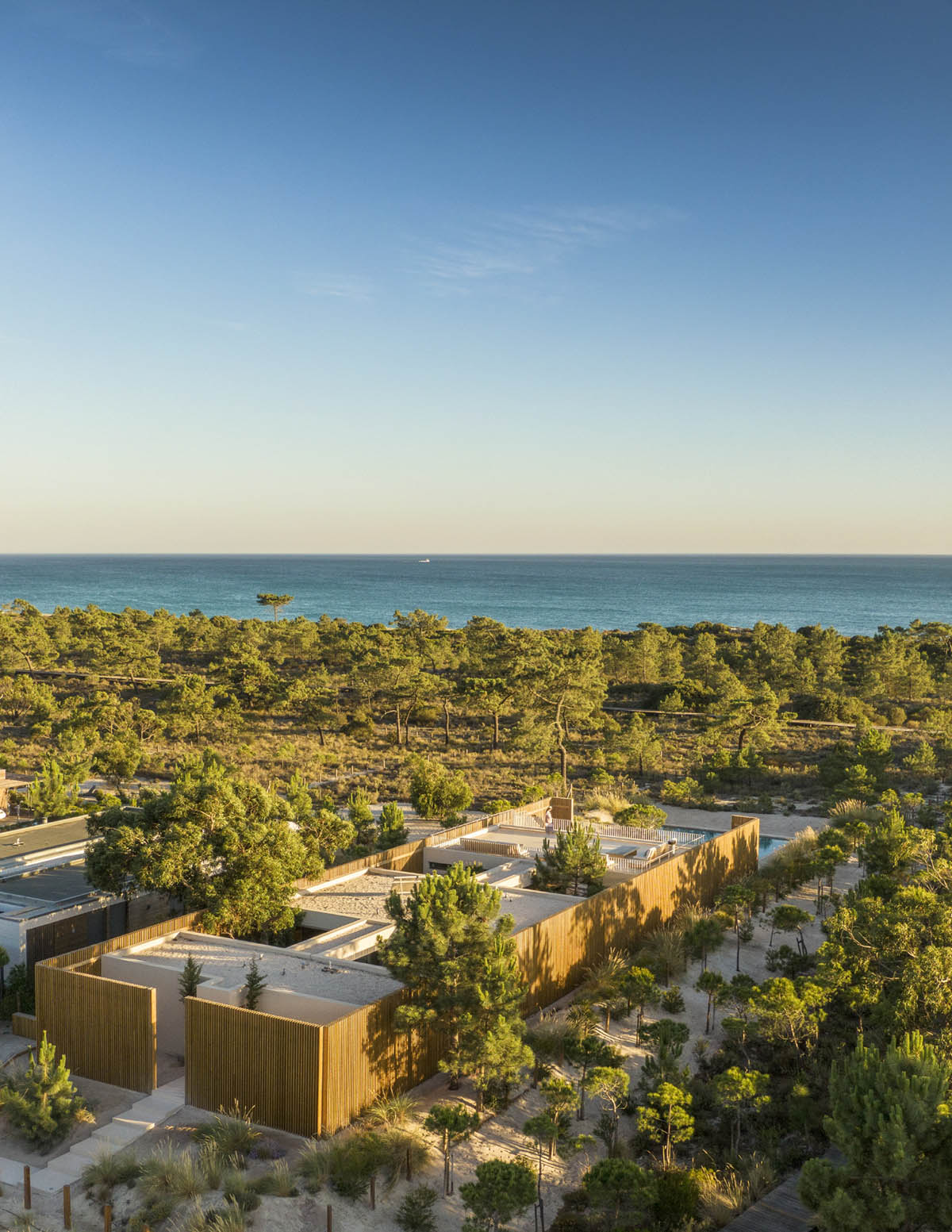 Palisade House is wrapped by a long palisade in fir wood to protect dunes in Troia, Portugal 