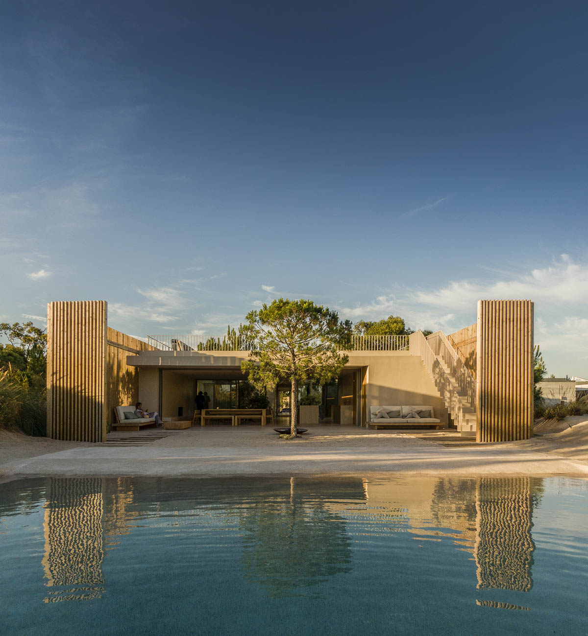 Palisade House is wrapped by a long palisade in fir wood to protect dunes in Troia, Portugal 
