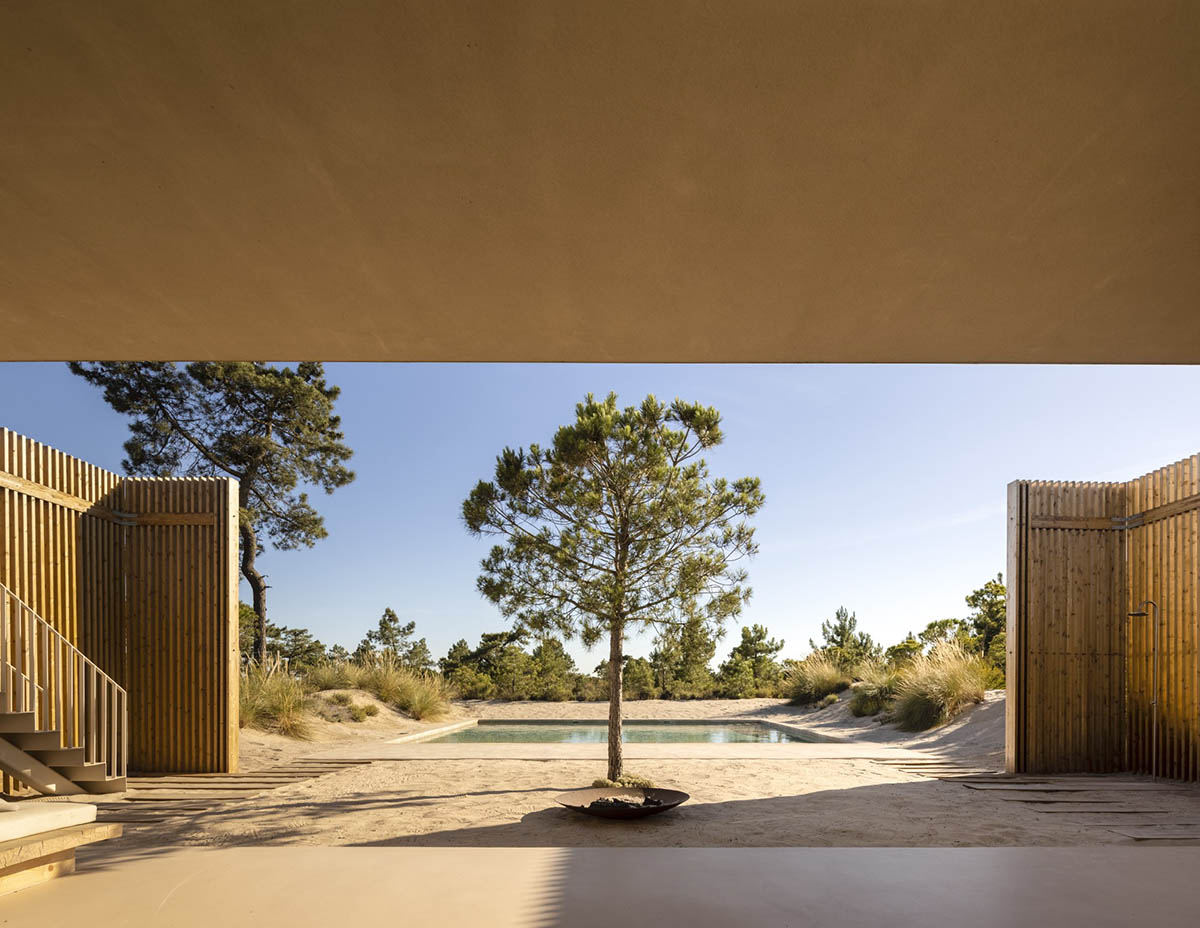 Palisade House is wrapped by a long palisade in fir wood to protect dunes in Troia, Portugal 