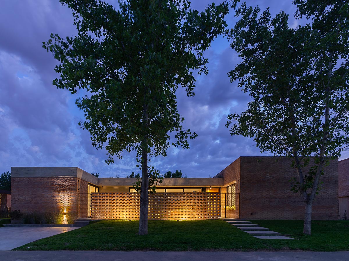Nómade Arquitectura creates urban filter with large interlocked brick wall for house in Argentina