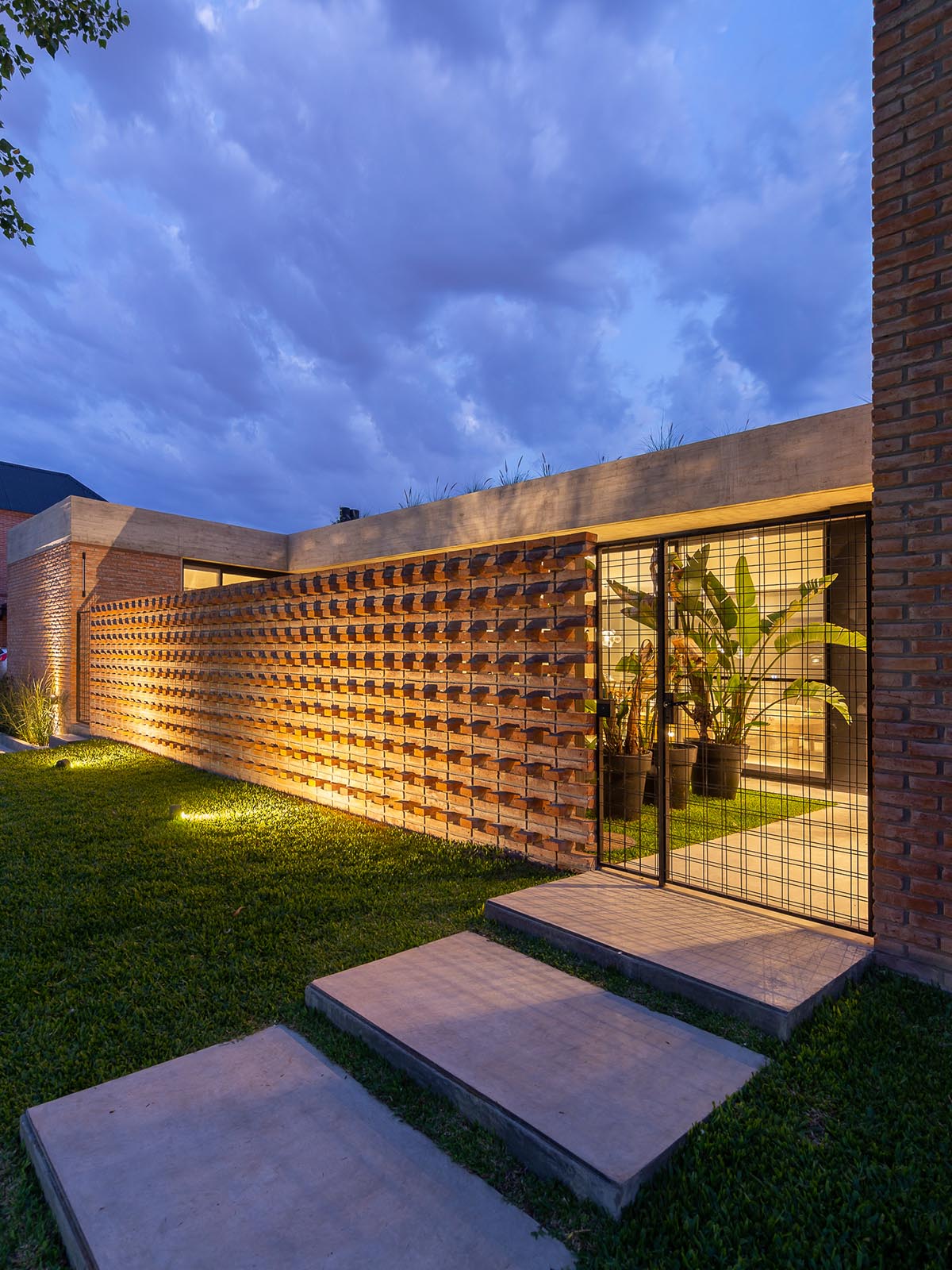 Nómade Arquitectura creates urban filter with large interlocked brick wall for house in Argentina