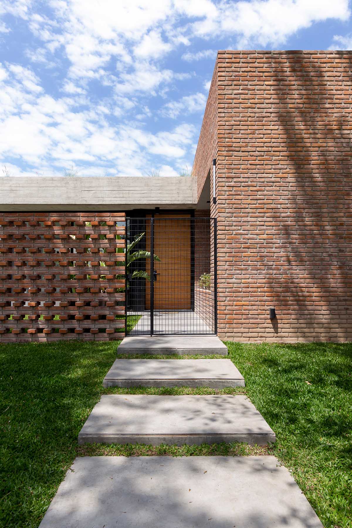 Nómade Arquitectura creates urban filter with large interlocked brick wall for house in Argentina